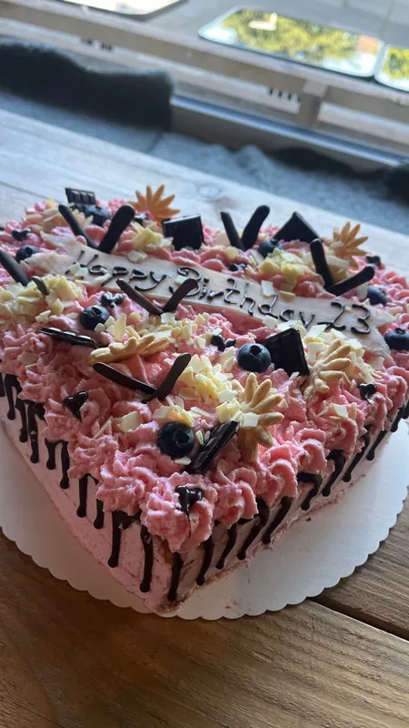 Torte mit rosa Sahnetupfen, Beeren und Schokoladendekor