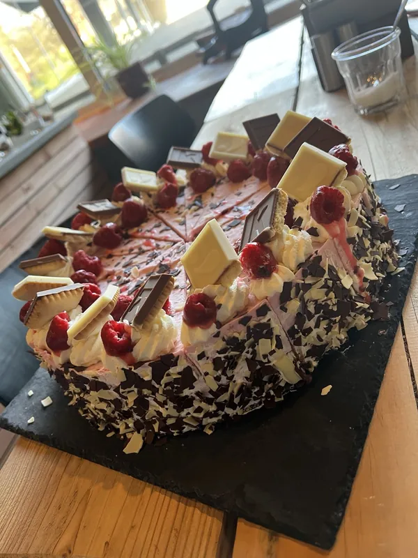 Kirschtorte mit weißen Schokoladensplittern auf einer Schieferplatte