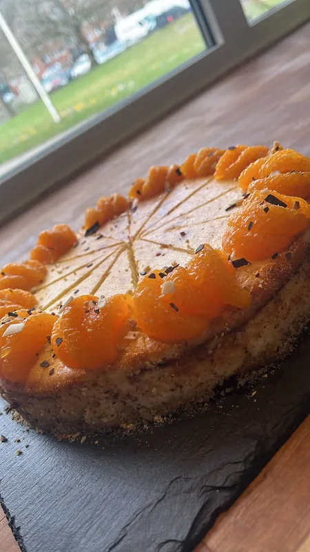 Mandarinen-Sahnetorte auf einer Schieferplatte am Fenster