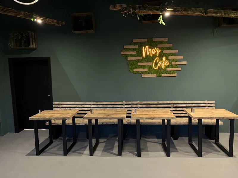 Lange Tafel für Gruppen im Nebenraum von Mo's Café, im Hintergrund der Leuchtschriftzug